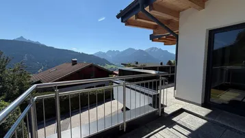 Balkon mit modernem Metallgeländer und atemberaubendem Panoramablick auf die umliegende Bergwelt.