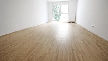 Helles, leeres Zimmer mit Parkettboden und großen Fenstern, bereit zur individuellen Gestaltung.