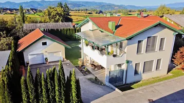 Luftaufnahme des gepflegten Einfamilienhauses mit Doppelgarage und malerischer Berglandschaft im Hintergrund.