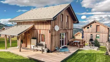 Charmantes Holzhaus mit großer Holzterrasse, Essbereich im Freien und Bergblick.