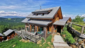 Charmantes Holzchalet in alpiner Landschaft mit weitem Blick auf die Berge und Wälder.