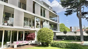 Moderne Wohnanlage mit großzügiger Gartenfläche und mehreren Balkonen, umgeben von viel Grün.
