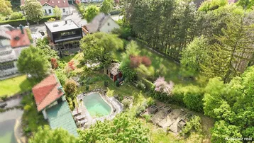 Luftaufnahme des Anwesens mit großem Garten, Pool und umgebender Natur.