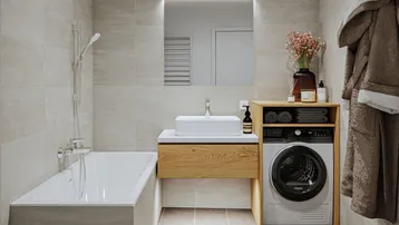 Modernes Badezimmer mit Badewanne, Waschbecken und integrierter Waschmaschine, hell gefliest.