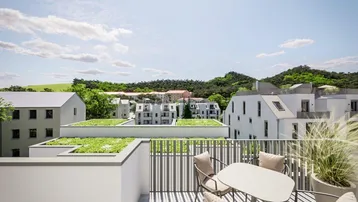 Moderne Dachterrasse mit bequemen Sitzgelegenheiten und weitem Blick über die umliegenden Gebäude und grüne Hügel.