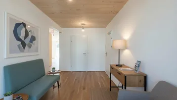 Heller Flur mit Holzdecke, weiß gestrichenen Wänden und modernem Mobiliar.
