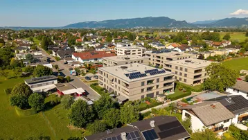 Weitläufige Luftaufnahme von Wohngebäuden mit Solaranlagen und Bergblick.