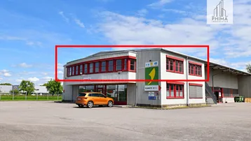 Außenansicht eines modernen Geschäftsgebäudes mit großen Fenstern und einem Parkplatz davor.