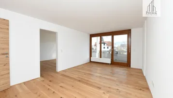 Helles Zimmer mit neuem Holzboden und großen Fenstern, die viel Tageslicht hereinlassen.