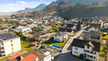 Panoramablick aus der Luft auf eine Siedlung mit Bergen im Hintergrund.