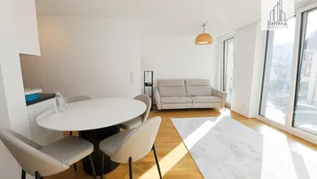 Helles Wohn- und Esszimmer mit Parkettboden, modernen Möbeln und großen Fenstern.