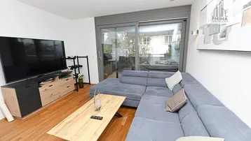 Helles Wohnzimmer mit großem Sofa, TV-Möbel und Zugang zum Balkon.