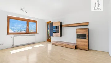 Helles Wohnzimmer mit Holzboden, modernen Möbeln und einem schönen Bergblick durch das große Fenster.