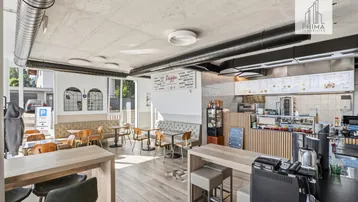 Geräumiger Gastraum eines Bistros mit Holzböden, modernen Möbeln und großen Fenstern.