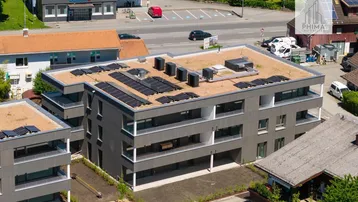 Moderne Wohnanlage aus der Vogelperspektive mit Flachdach, Solaranlagen und begrünten Dächern.
