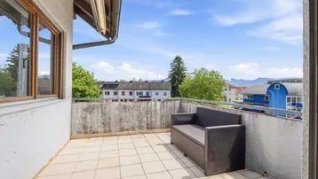 Gefliester Balkon mit Sitzgelegenheit und weitem Blick auf die umliegende Landschaft und Berge.