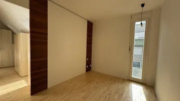 Helles Schlafzimmer mit Holzboden, Holzakzenten und Zugang zu einem französischen Balkon.