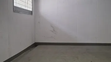 Tiefgaragenstellplatz mit Betonboden, kleiner Fensteröffnung und Leuchtstoffröhrenbeleuchtung.