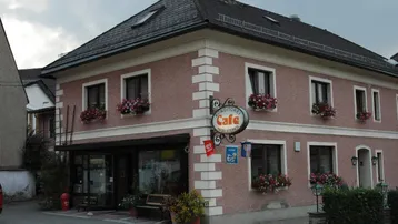 Traditionelles Gebäude mit Konditorei-Café im Erdgeschoss, geschmückt mit Blumenkästen an den Fenstern.