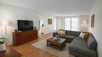 Helles Wohnzimmer mit großem Ecksofa, Holzboden und einem TV-Möbel aus Holz.