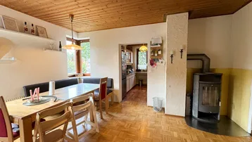 Gemütlicher Essbereich mit Holztisch, Sitzbank und Kaminofen, ideal für gesellige Abende.