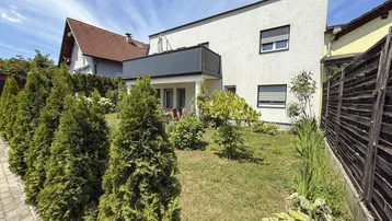 Modernes Haus mit gepflegtem Rasen und einer Reihe von Zypressen im Vorgarten.