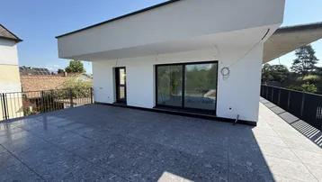 Große, geflieste Terrasse mit moderner Architektur und Blick ins Grüne, ideal für Entspannung im Freien.