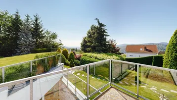 Terrasse mit Glasgeländer bietet einen weiten Blick über die grüne Landschaft und die Umgebung.