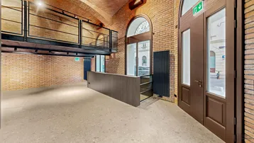 Geräumiger Gewerberaum mit freigelegten Ziegelwänden, Gewölbedecke und einer modernen Galerieebene.