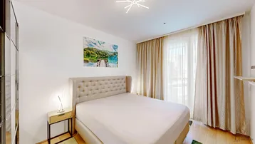 Gemütliches Schlafzimmer mit Doppelbett, Spiegelschrank und Zugang zu einem französischen Balkon.