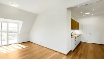 Heller Wohnbereich mit Holzboden, Dachschrägen und Zugang zu einem französischen Balkon.