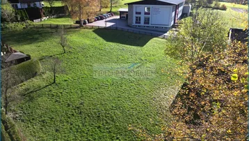 Luftaufnahme eines großen grünen Grundstücks mit umliegenden Gebäuden und Bäumen in sonniger Lage.