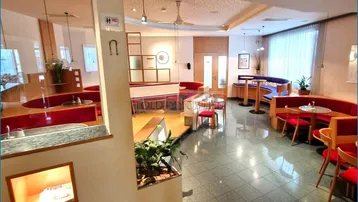 Geräumiger Innenbereich eines Restaurants oder einer Bar mit verschiedenen Sitzbereichen und einer Theke im Hintergrund.