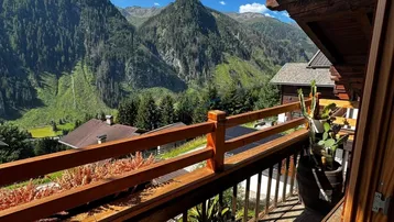 Sonniger Balkon mit Holzgeländer und atemberaubendem Blick auf die umliegenden Berge.