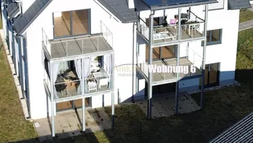 Moderne Wohnanlage mit mehreren Balkonen und Terrassen, einige davon möbliert und mit Solaranlage.