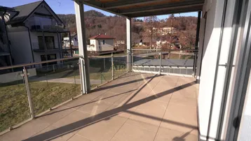 Heller Balkon mit Fliesenboden und Glasgeländer, bietet einen weiten Blick auf die umliegende Landschaft.