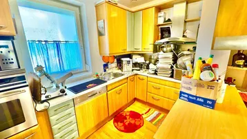 Funktionale Küche mit Holzschränken, Fenster und integrierten Geräten.