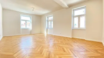 Helles, leeres Wohnzimmer mit Fischgrätparkettboden und hohen Decken, ideal für individuelle Gestaltung.