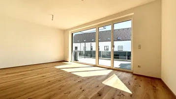Helles Wohnzimmer mit neuem Parkettboden und großzügigem Zugang zu einer Außenterrasse.