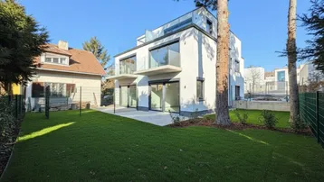 Modernes Mehrfamilienhaus mit weißer Fassade, Balkonen, Dachterrasse und großem Gartenbereich.