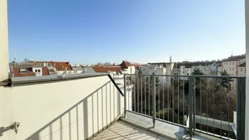 Heller Balkon mit Fliesenboden und weitem Blick über die Dächer der Stadt.