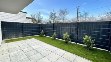 Gepflasterte Terrasse mit kleinem Rasenbereich und Sichtschutz, ideal für entspannte Stunden im Freien.