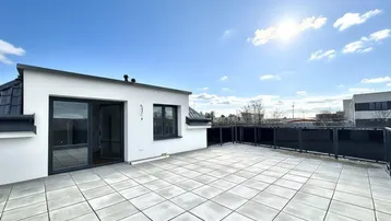 Große, sonnige Dachterrasse mit modernen Fliesen und Glasgeländer, ideal für Entspannung im Freien.