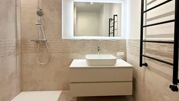 Modernes Badezimmer mit begehbarer Regendusche, Einzelwaschbecken und beheiztem Handtuchhalter.