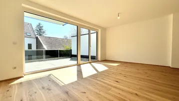 Helles Wohnzimmer mit neuem Parkettboden, großen Fenstern und Zugang zu einer Terrasse.