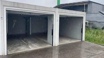 Zwei separate Garagen mit geöffneten Toren und Betonkonstruktion im Freien.
