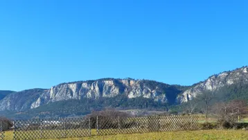 Weitläufiger Blick auf die umliegende Berglandschaft unter klarem blauem Himmel.