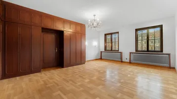 Helles Zimmer mit Einbauschränken aus Holz, Fischgrätparkett und Kronleuchter.