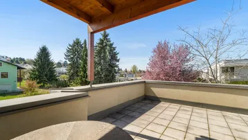 Geräumige Terrasse mit Fliesenboden, Holzdecke und weitem Blick ins Grüne.