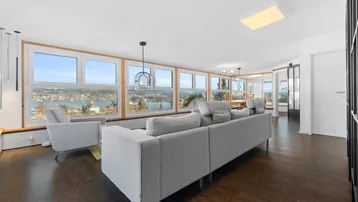 Helles Wohnzimmer mit Seeblick, Holzboden und moderner Einrichtung, offen zum Essbereich.